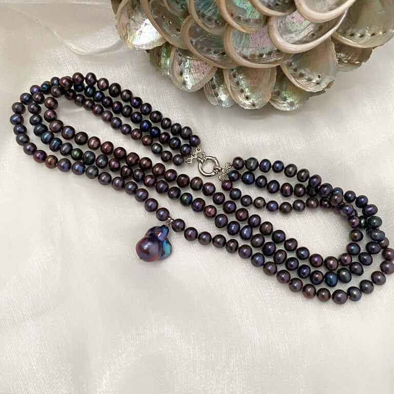 Black pearl necklace with a heart-shaped pendant on a white background