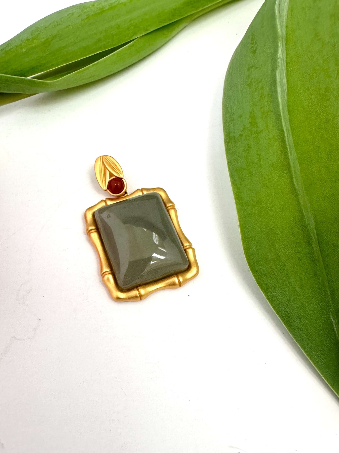 Bamboo style jade pendant with red agate in gold vermeil, showcasing a unique jade stone framed in a bamboo-inspired design.