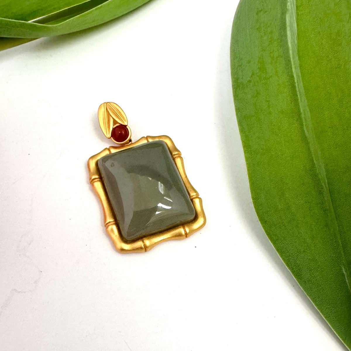 Bamboo style jade pendant with red agate in gold vermeil, showcasing a unique jade stone framed in a bamboo-inspired design.