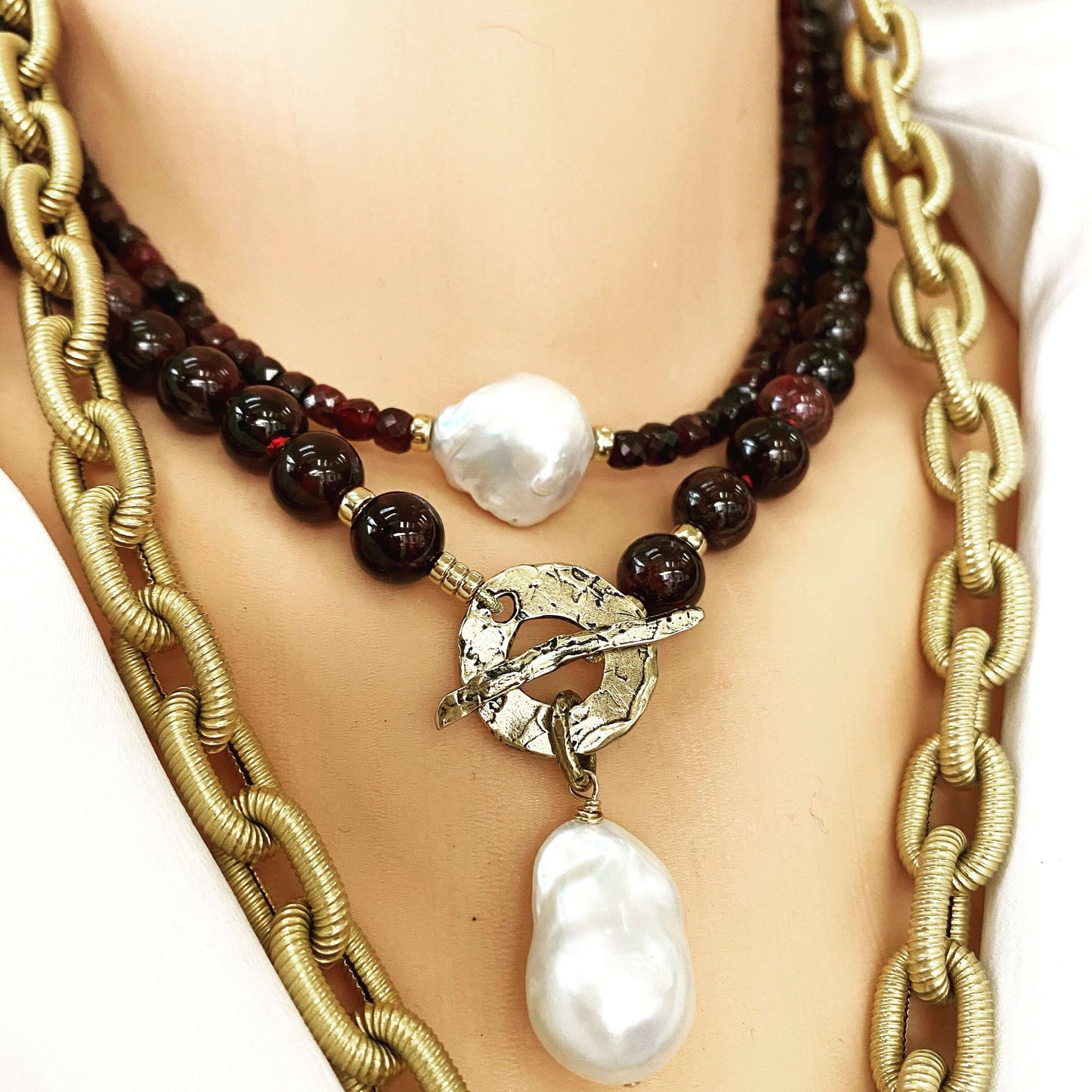Garnet pearl necklace layered with gold chain featuring baroque pearl pendant