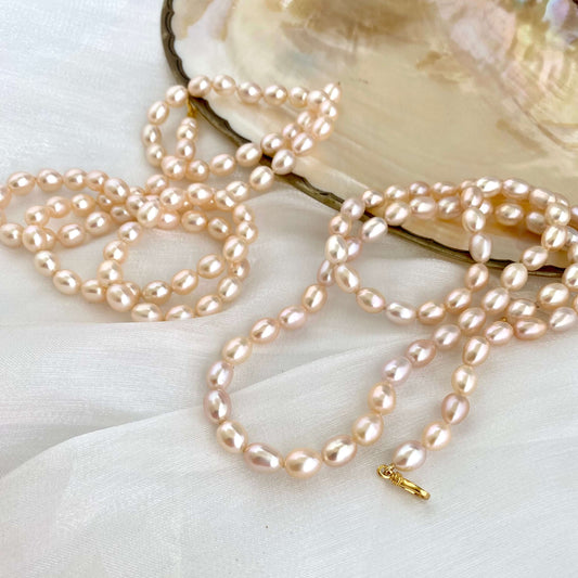Pearl necklace on a white surface with an open shell in the background