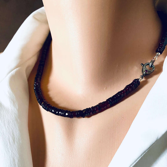 Garnet beaded necklace with diamond and ruby pavé clasp displayed on a mannequin against white fabric.