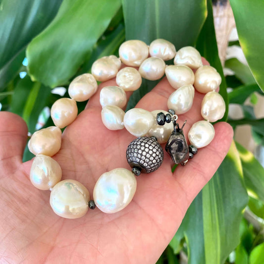 Ivory baroque pearl bridal necklace held in hand highlighting organic pearl shapes and contrast clasp