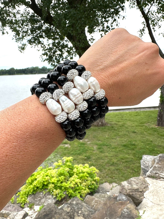 Five black onyx bracelets stacked on a model’s wrist