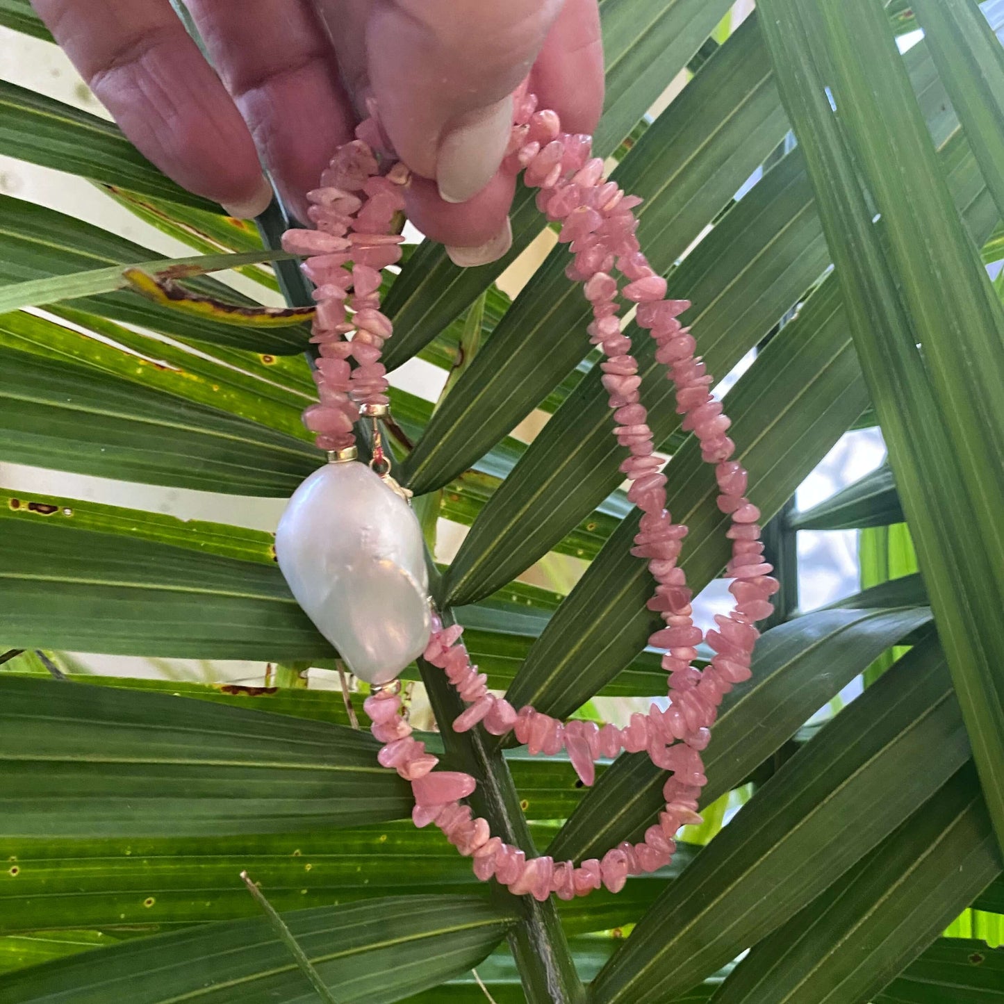 Rhodochrosite pearl necklace held in hand