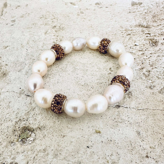 White pearl stretch bracelet with gold rhinestones on white tabletop