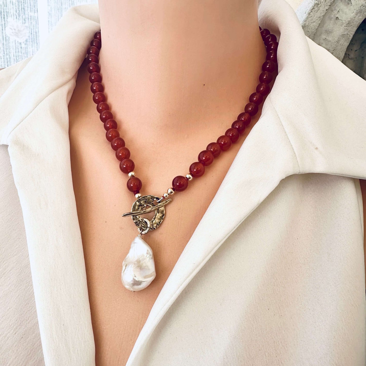 Red agate toggle necklace shown on mannequin in studio lighting, frontal close-up