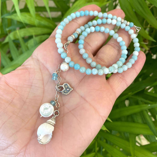 Amazonite pearl necklace held in hand against green leaves