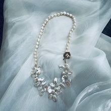 Load image into Gallery viewer, Add a touch of organic elegance to your look with this stunning 25" white Keshi pearls necklace, featuring a unique asymmetrical design that showcases both petal-shaped and nugget pearls.
At the side, a beautiful golden palm leaf toggle clasp adds a tropical flair