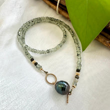 Carica l'immagine nel visualizzatore di Gallery, This necklace features a delicate chain of soft, translucent faceted green Prehnite rondelle beads, beautifully complemented by a striking Tahitian baroque pearl as the centerpiece pending from a cold filled toggle clasp. 18"inches long