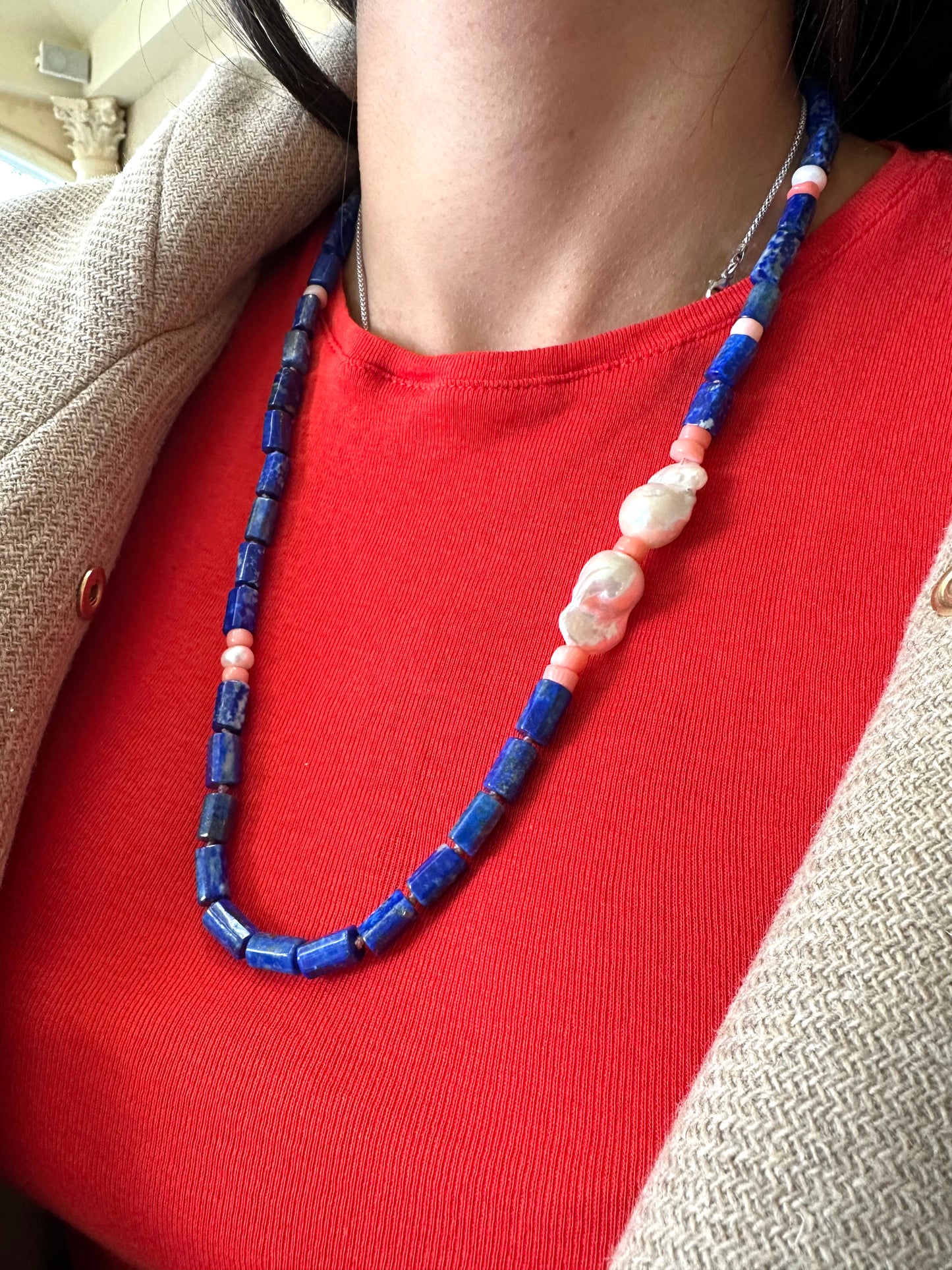 Lapis lazuli necklace with pink coral and baroque pearls showcased on a model's neck, featuring vibrant colors and textures.