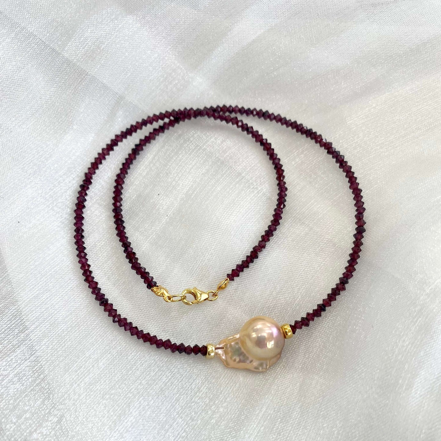Red garnet baroque pearl necklace featuring golden pink pearl pendant and rich red garnet beads.