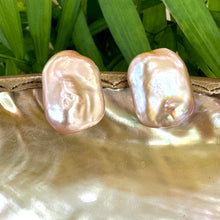 Load image into Gallery viewer, Golden pink rectangle baroque pearl stud earrings hanging from white pearl shell with green leaf background, designed and handmade in Canada.