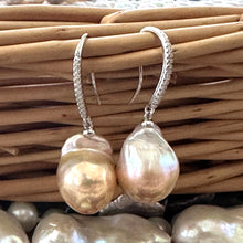 Load image into Gallery viewer, Golden pink baroque pearl dangle earrings resting on wicker basket, sterling silver CZ pavé design handmade in Canada.