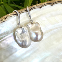 Load image into Gallery viewer, White baroque pearl bridal earrings resting on pearl shell and foliage background, handmade in Canada.