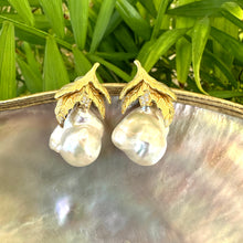Load image into Gallery viewer, Nature-inspired Baroque Pearl Earrings with gold vermeil oak leaf design photographed on white shell and green leaf background.