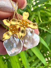 Load image into Gallery viewer, Keshi Pearl Earrings with white petal pearls and gold vermeil flower hooks held in hand against green leaf background.