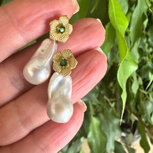 Load image into Gallery viewer, Chrome diopside pearl earrings held in hand for size comparison against green leaf background