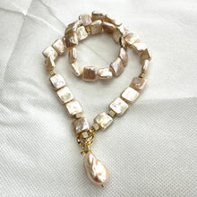 Load image into Gallery viewer, Full view of golden baroque pearl toggle necklace on white backdrop — handcrafted statement jewelry featuring square pearls and gold clasp