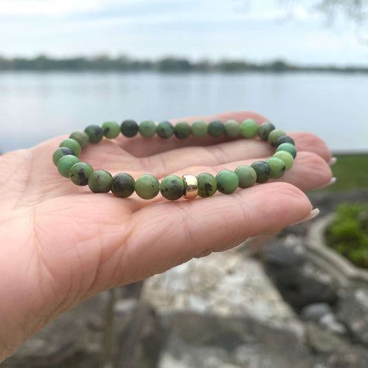 Chrysoprase stretch bracelet featuring 6mm beads with 14K Gold Filled accent, shown on hand near a lake.