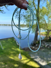 Load image into Gallery viewer, Blue Larimar Lariat Necklace held against lake and grass background — natural gemstone and pearl necklace handcrafted by Loulia Pearl Jewelry