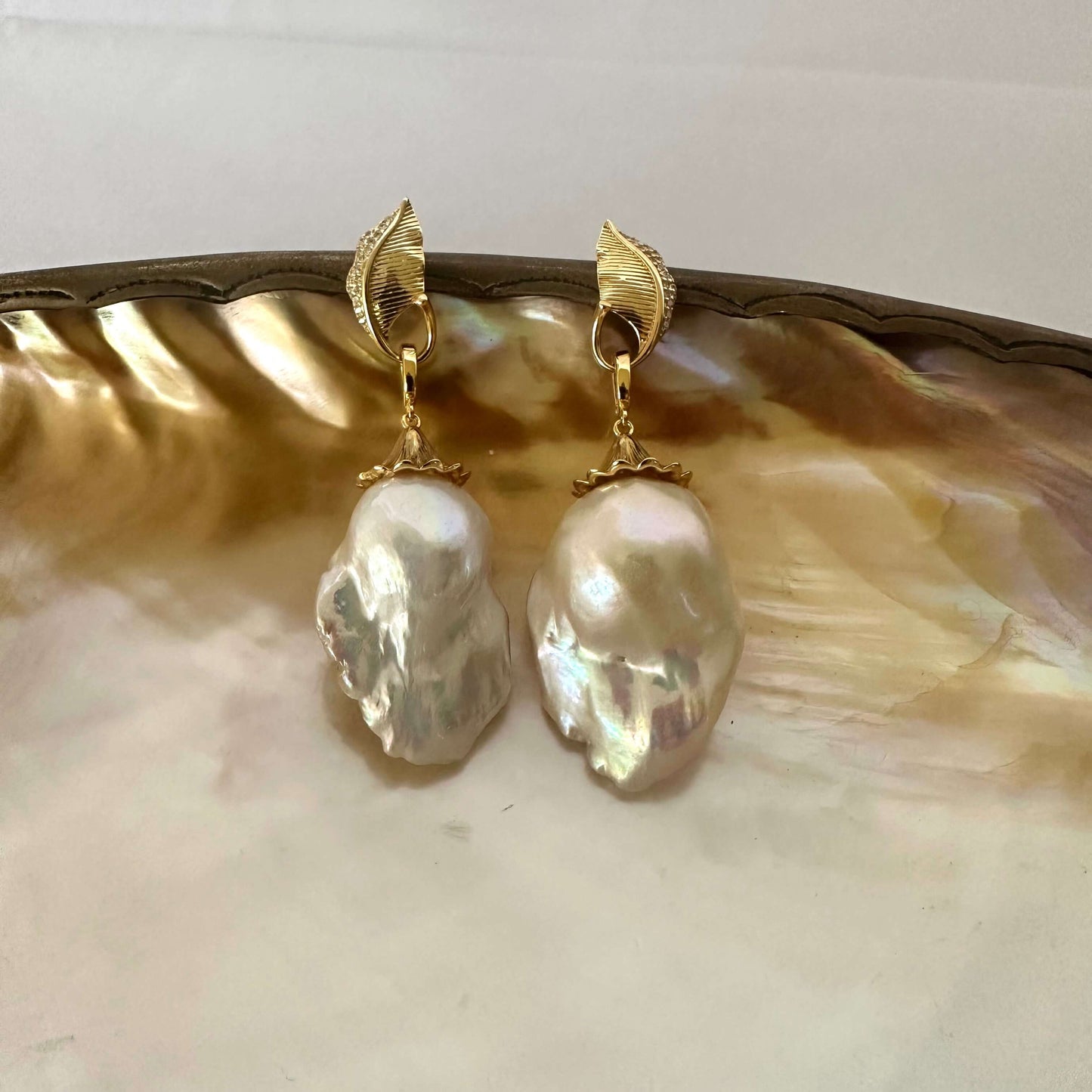 Leaf Design Pearl Earrings with gold vermeil accents and baroque pearl drops on a decorative plate.
