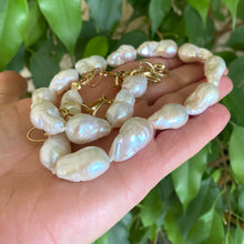 Load image into Gallery viewer, Baroque pearl gold chain necklace held in hand against green leaves — handcrafted pearl and gold statement jewelry by Loulia Pearl Jewelry