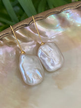 Carica l'immagine nel visualizzatore di Gallery, White freshwater pearl drop earrings in gold vermeil displayed on white pearl shell with green leaf background, designed and handmade in Canada.