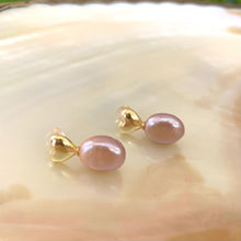 Load image into Gallery viewer, Heart Pearl Earrings – gold version close-up against white pearl shell
