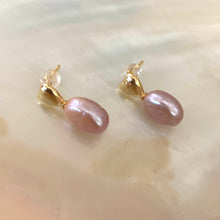 Load image into Gallery viewer, Heart Pearl Earrings – gold version close-up against white pearl shell