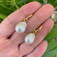 Carica l'immagine nel visualizzatore di Gallery, White Baroque Pearl Earrings – held by hand against natural green foliage
