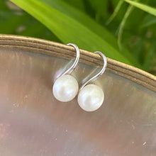 Load image into Gallery viewer, Button Pearl Earrings – silver pair displayed on pearl shell with green foliage