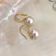 Load image into Gallery viewer, Button Pearl Earrings – gold version close-up displayed on white pearl shell