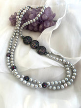 Load image into Gallery viewer, Grey Pearl Necklace with double strands of pearls arranged beside amethyst ornament on white fabric background.