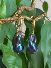Load image into Gallery viewer, Handmade baroque pearl hoop earrings in black peacock tones shown close up on green leaf background