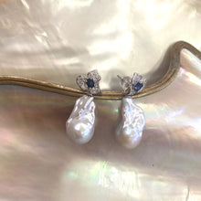 Load image into Gallery viewer, Close view of sapphire and emerald stud earrings with pearl drops on shell background