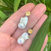 Load image into Gallery viewer, Citrine stud earrings with pearl drops held in hand against green leaf background