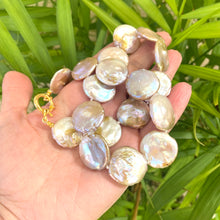 Load image into Gallery viewer, Large coin pearl necklace held in hand against green leaf background
