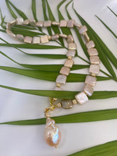 Load image into Gallery viewer, Golden baroque pearl toggle necklace displayed on green leaf branch — elegant handcrafted pearl jewelry photographed in natural light