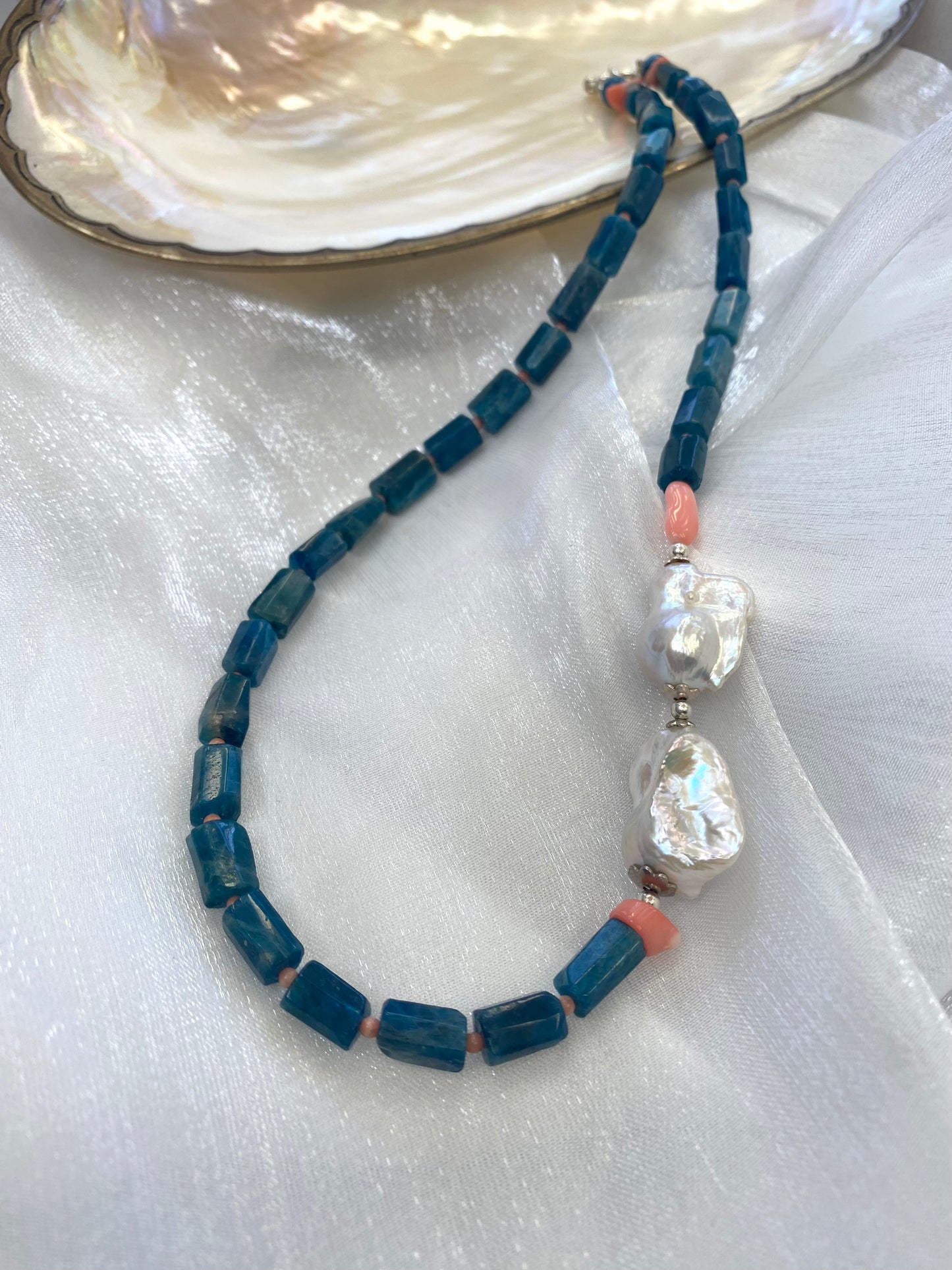 Detailed view of blue apatite coral pearl necklace against white background — sterling silver clasp and colorful gemstone design