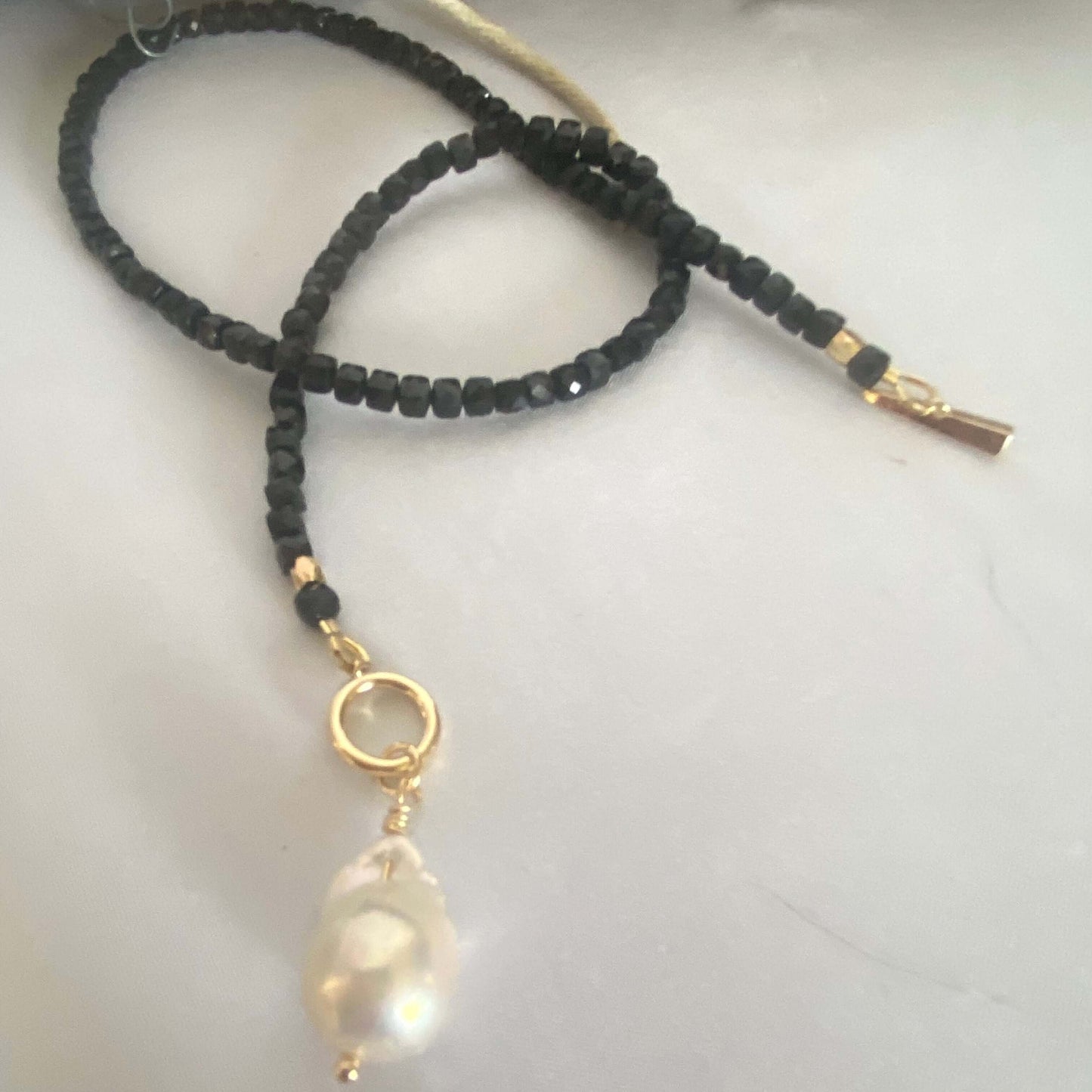 Black Tourmaline choker necklace with pearl charm, featuring sparkling faceted cube beads and a gold clasp.