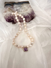Lade das Bild in den Galerie-Viewer, White Nugget Pearl Necklace with Amethyst Pendant – 'Viola' Collection on a soft fabric background.