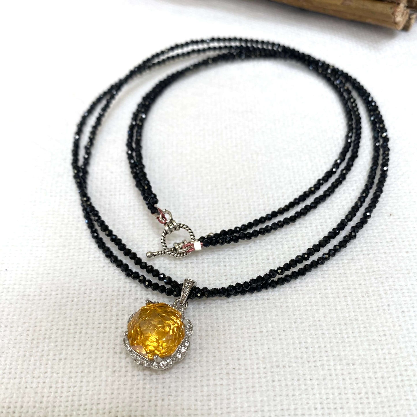 Black spinel and citrine pendant necklace on white background, handmade silver design