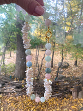 Load image into Gallery viewer, Aquamarine Morganite Necklace – held by hand against green foliage backdrop