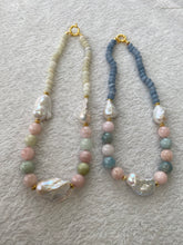 Lade das Bild in den Galerie-Viewer, Morganite and jade necklace with baroque pearls beside blue gemstone necklace on white mat, showcasing color contrast and design variety.