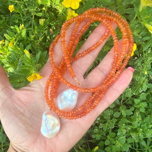 Carnelian lariat necklace featuring vibrant orange beads and two baroque pearls, perfect for stylish versatility.