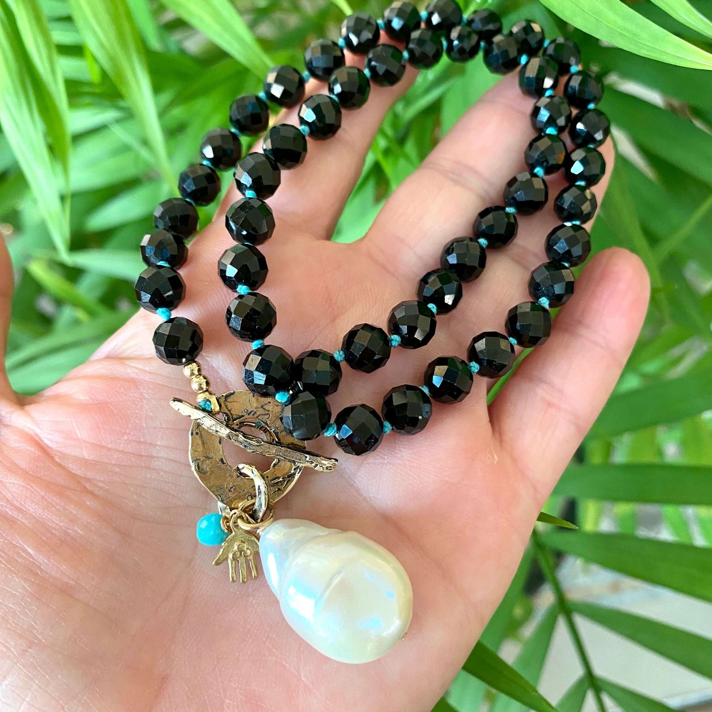 Black tourmaline baroque pearl toggle necklace photographed in hand emphasizing baroque pearl size