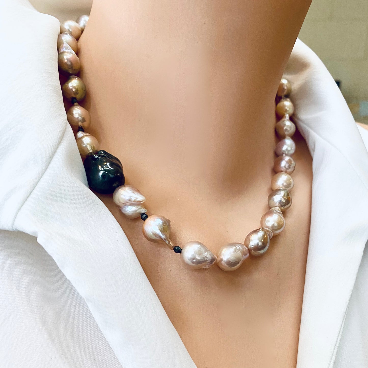 Side close-up of pink baroque pearl necklace worn by mannequin, black rhodium silver clasp visible.