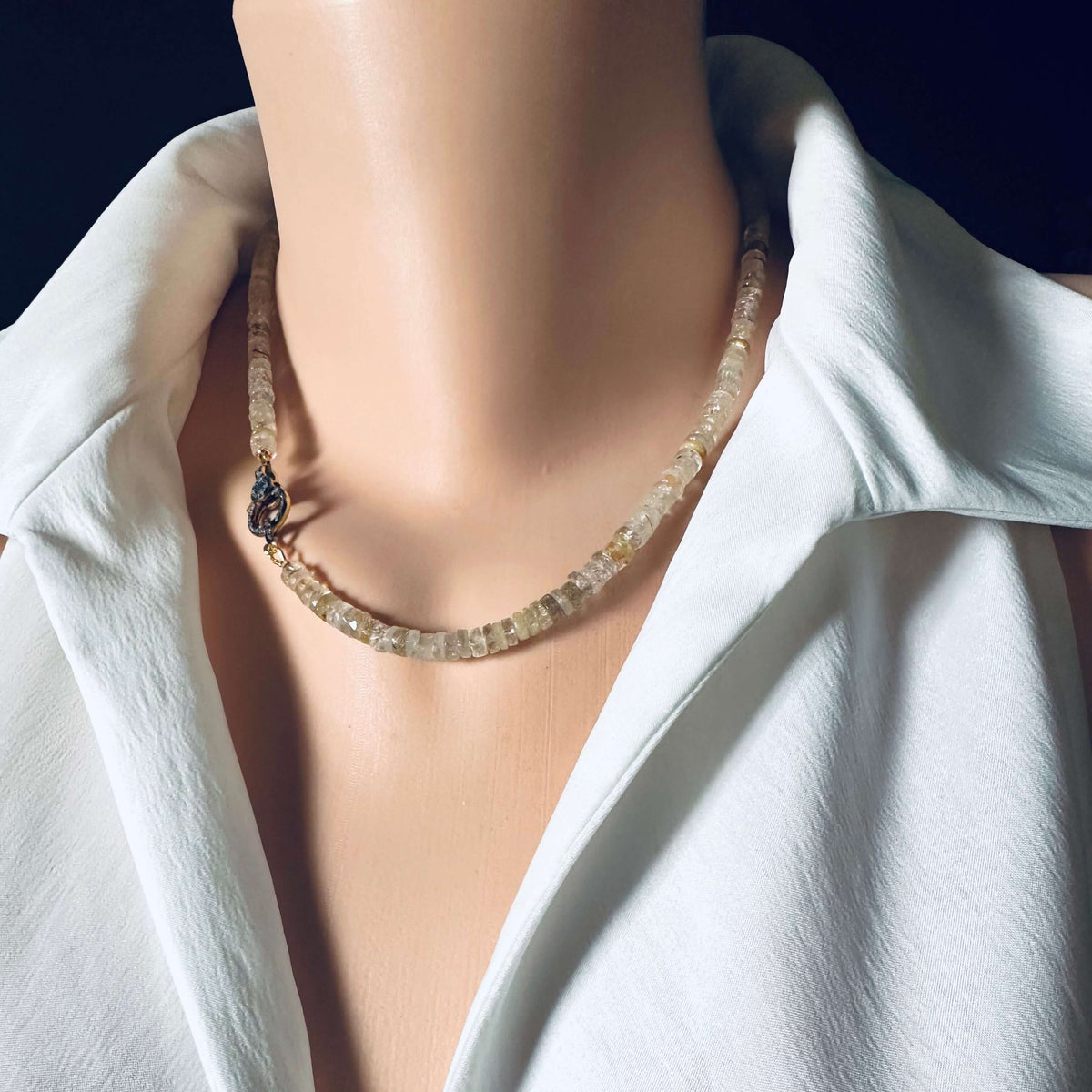 Rutilated quartz gemstone necklace displayed on a mannequin, featuring faceted beads and an oxidized vermeil pavé clasp.