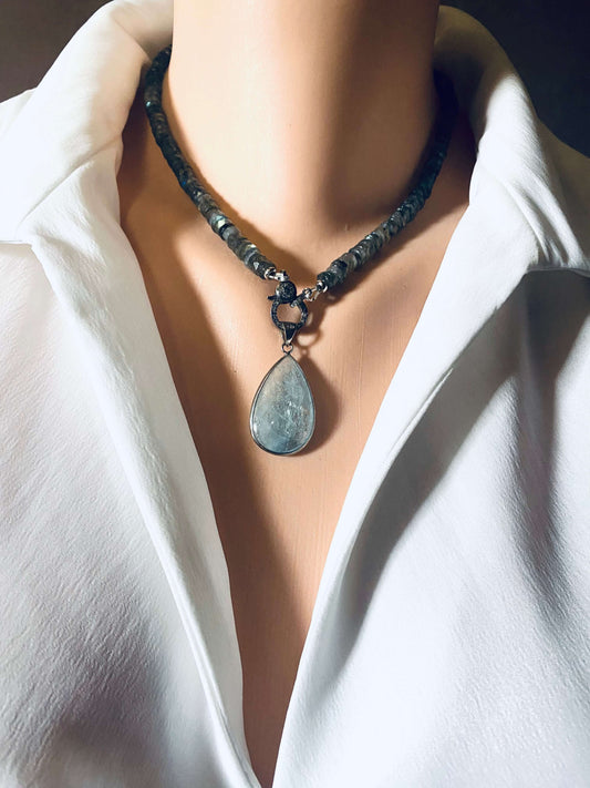 Aquamarine teardrop pendant in oxidized sterling silver worn on a necklace with beads, showcasing its organic beauty.